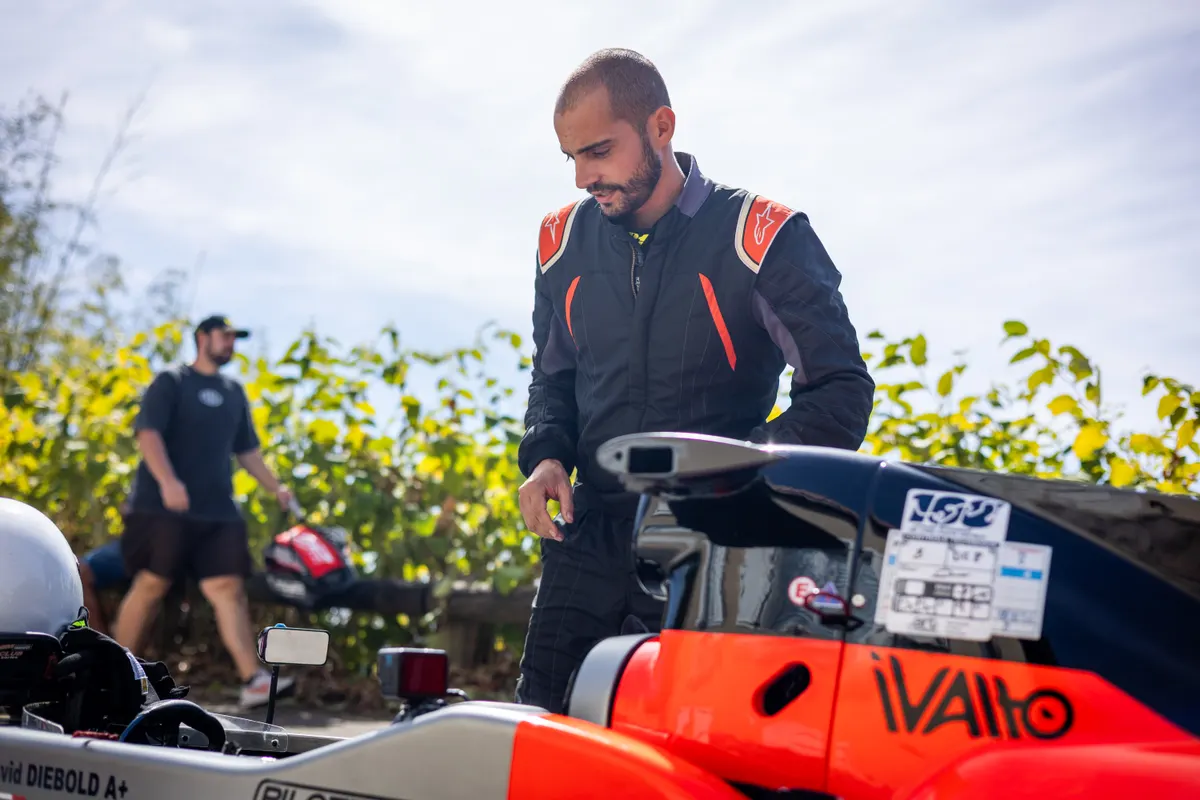 Pilote en combinaison se préparant à côté de sa monoplace
