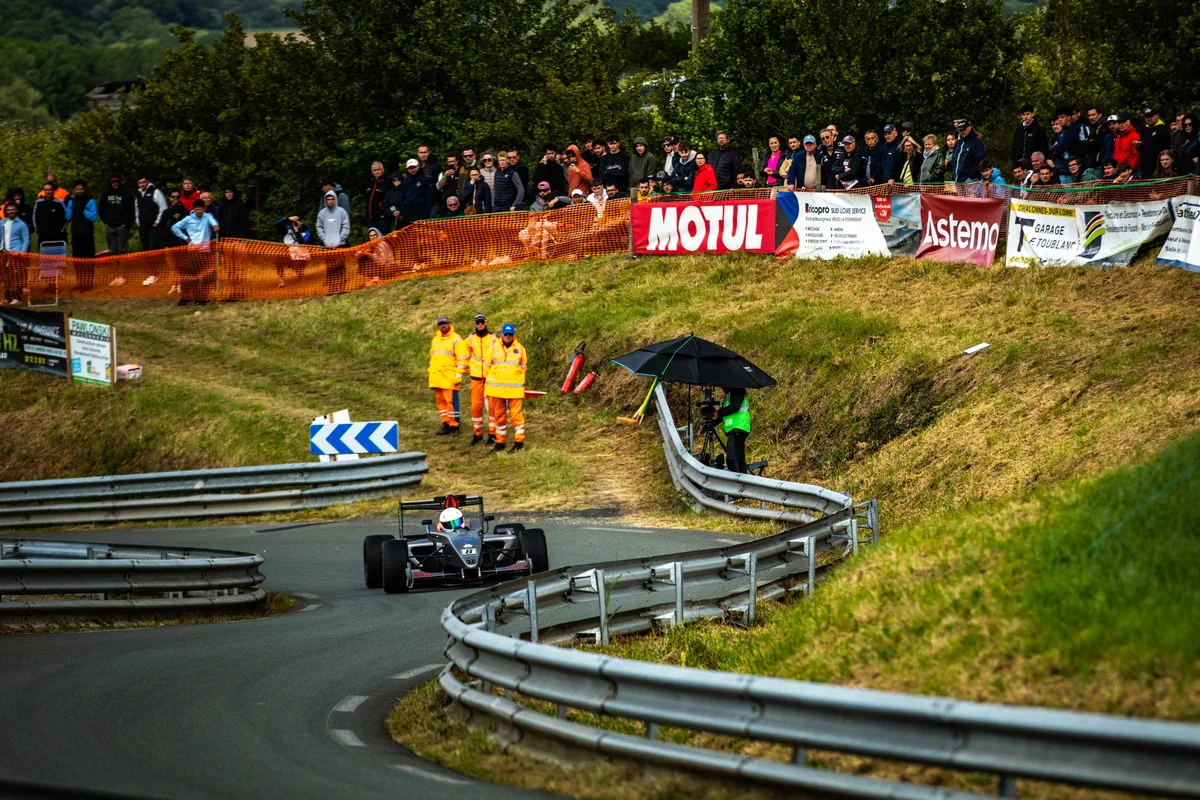 La monoplace Diebold Sport numéro 8 vue de face dans un virage de La Pommeraye, avec les spectateurs et les panneaux partenaires en arrière-plan
